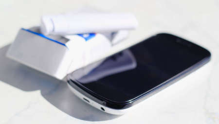 A lighter, cigarettes and mobile phone on white table の写真素材