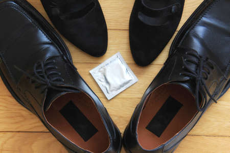 Concept of safe sex; man and woman shoes and a condom on the floor の写真素材