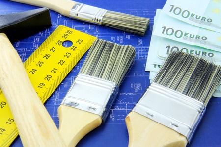 Renovating a home concept; hammer, meter, brushes and money on blue print の写真素材