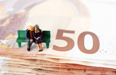 Old couple on a bench. Retired. Pension. Safe in older years. On Euro banknote. Miniature people.の写真素材