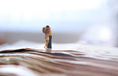 Yoiung couple in love. In a hug. On Euro paper money. Wealthy. Happy. Successful. Miniature people.の写真素材