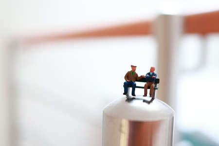 Miniature retired people sitting on a bench and having conversation.の写真素材