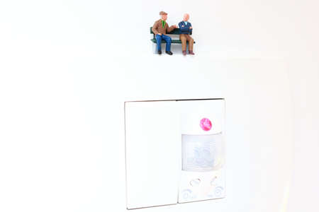 Miniature retired people sitting on a bench and having conversation.の写真素材