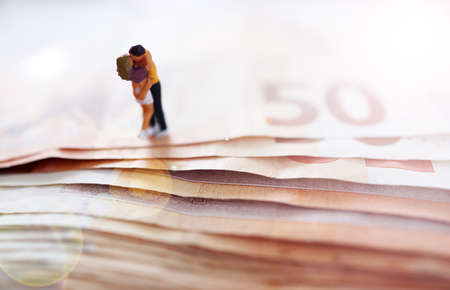 Miniature people stand on a stack of 500 euro banknotes.の写真素材