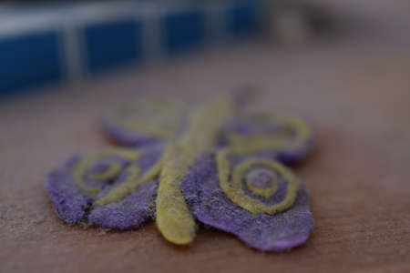 Close-up of a handmade felt flower on a wooden surface.の写真素材