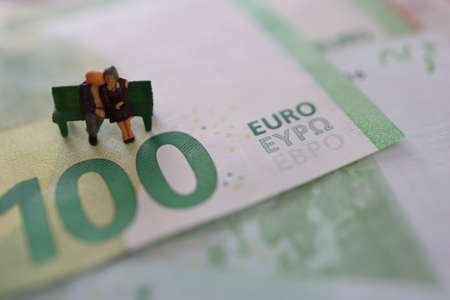 Elder pair, woman and man, sitting on a bench on Euro paper money.の写真素材