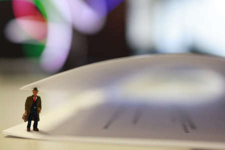 Miniature business people under a sheet of envelope paper in real office.の写真素材