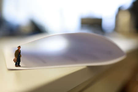 Miniature business people under a sheet of envelope paper in real office.の写真素材