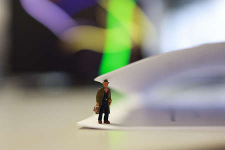 Miniature business people under a sheet of envelope paper in real office.の写真素材