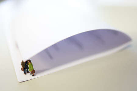Miniature business people under a sheet of envelope paper in real office.の写真素材