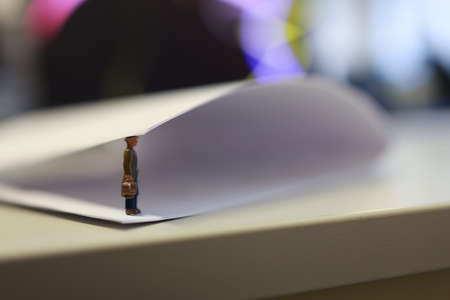 Miniature business people under a sheet of envelope paper in real office.