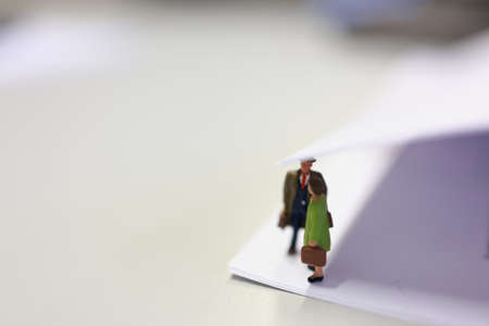 Miniature business people under a sheet of envelope paper in real office.の写真素材