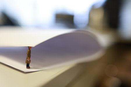 Miniature business people under a sheet of envelope paper in real office.の写真素材
