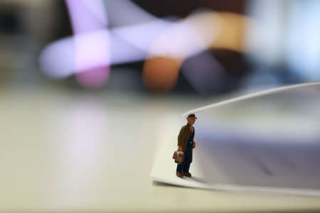 Miniature business people under a sheet of envelope paper in real office.の写真素材