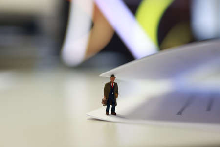 Miniature business people under a sheet of envelope paper in real office.の写真素材