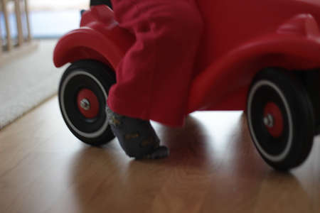 Little boy on a small truck in the house.