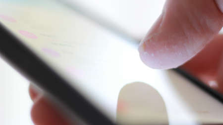 Male finger, macro of, while sliding on a mobile phone.の写真素材