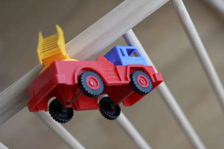 Small kid toy, a plastic fire truck on a wooden baby cot.の写真素材