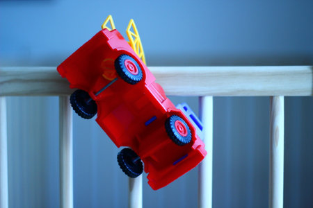 Plastic fire truck on a wooden baby cot.の写真素材
