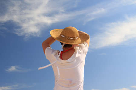 young woman in white dress and straw hat on the blue sky background