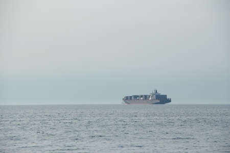 Large cargo ship in the open sea on a foggy day.