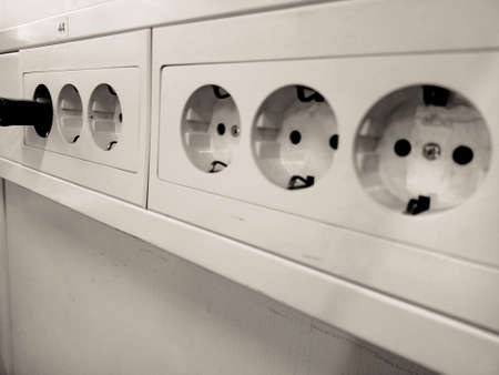 Close-up of a white electric socket on a white wall.