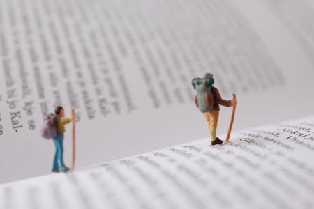 Miniature people : Hiker standing on the book with copy space