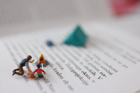 Miniature people working on a book. Selective focus and shallow depth of field.の写真素材