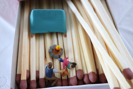 Miniature people standing on matchsticks in a box of matches.の写真素材