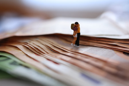 Miniature people: Couple on top of a stack of moneyの写真素材