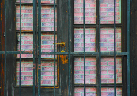 Old wooden door with iron handle and brick wall in the background.の写真素材