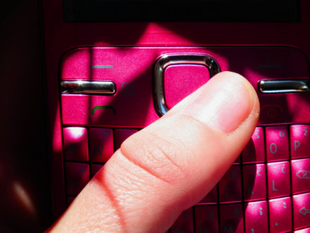 Closeup of a finger pressing a keypad of a mobile phoneの写真素材