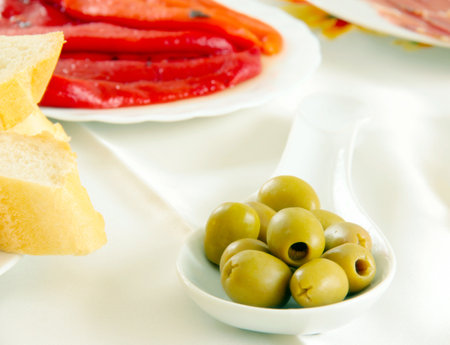 Green olives on a white plate with breadの写真素材