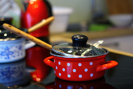 Red saucepan with white polka dots on the stove in the kitchenの写真素材