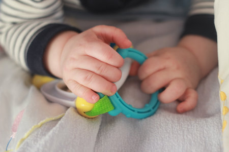 baby's hand holds a toy in the form of a ring.