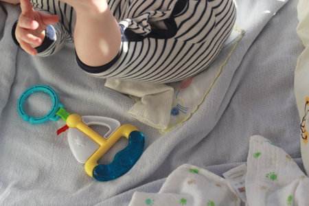 Little baby girl playing with toys on the bed in the room.