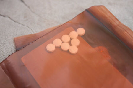 Dark brown sachets envelope with white tablets  Wood background