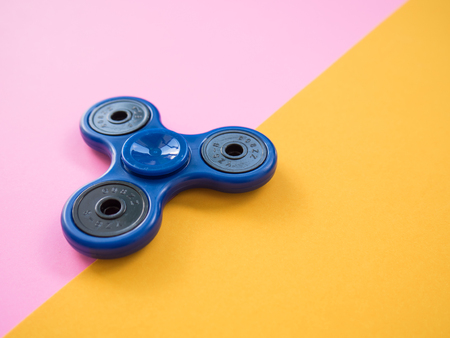 Blue Hand spinner on pink and yellow backgroundの写真素材