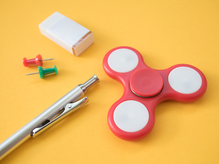 Pencil with colorful pins, eraser, hand spinner  and post it paper on yellow backgroundの写真素材