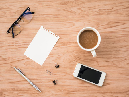 Flat Lay of coffee cup and office tools, smartphone and camera over old wooden background. The concept is wooden workspace with copy space background.の写真素材