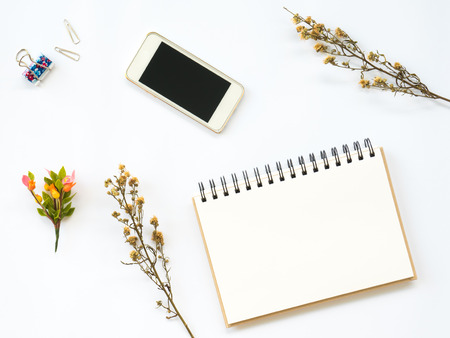 Flat Lay of dry leaf on workspaces with office tools, smartphone and stationary on white background.の写真素材