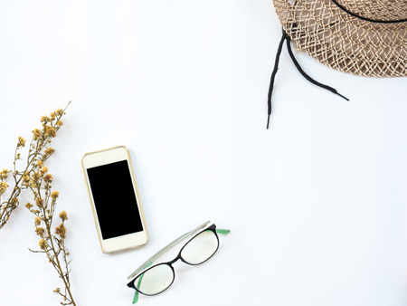 Flat Lay of dry leaf on workspaces with office tools, smartphone and stationary on white background.の写真素材