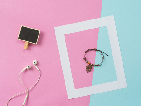Empty frame and label fwith earphone lat lay on blue and pink pastel background with copy space....