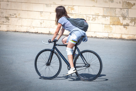 Brunette girl riding a bicycle around the city on a sunny dayの写真素材