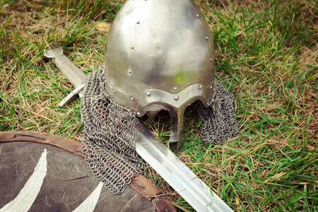 Helmet, sword and shield medieval warrior on the grassの写真素材