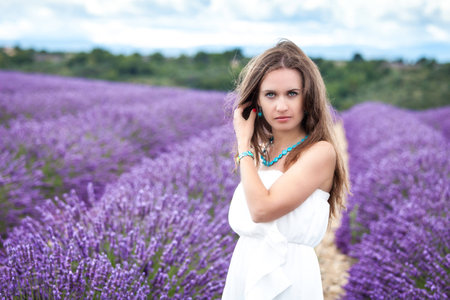 Beautiful girl with green eyes enjoying the scent of lavenderの写真素材