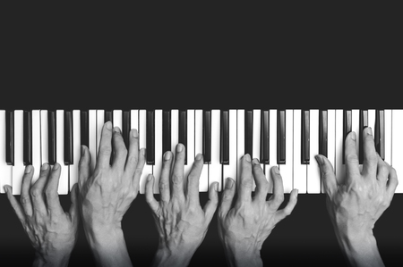 five hands playing on piano keys, black and whiteの写真素材