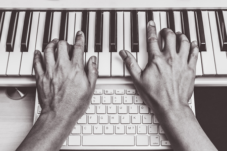 composer hands working on piano keys & computer keyboard. music production technologyの写真素材