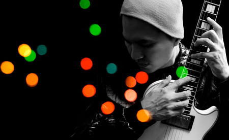 asian handsome musician playing electric guitar, isolated on black with colorful bokehの写真素材