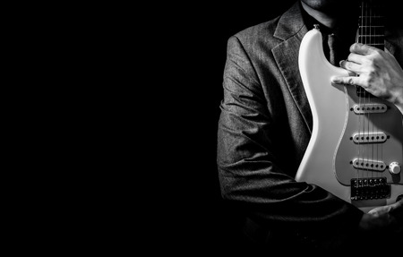 BW male musician in suit posing on white electric guitar, isolated on blackの写真素材